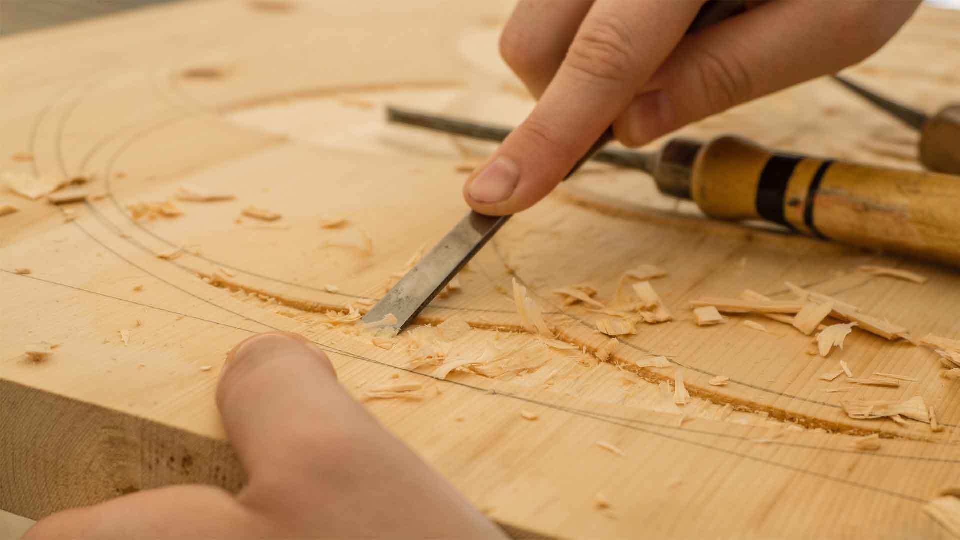 A craftsman hand-carving a curved pattern into solid wood