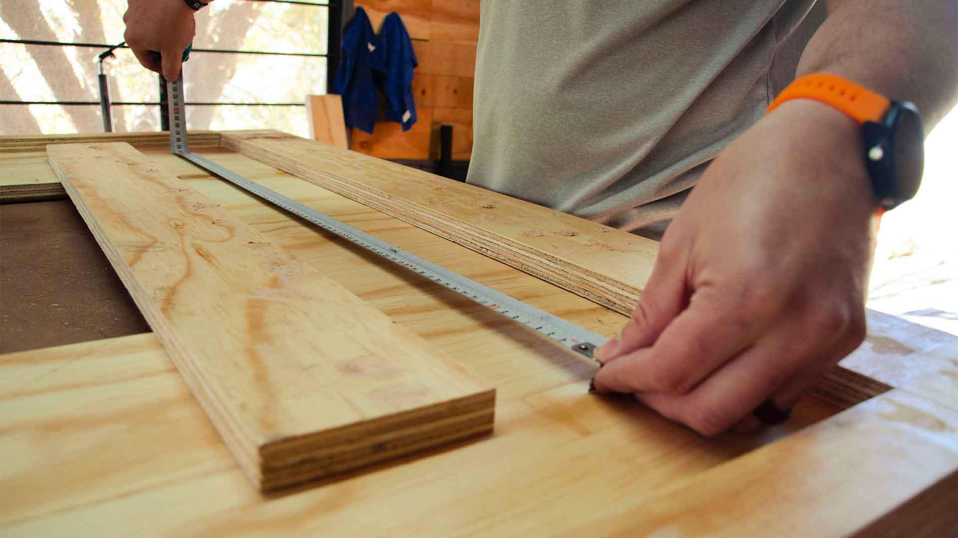 Measuring and squaring a plywood frame in the workshop
